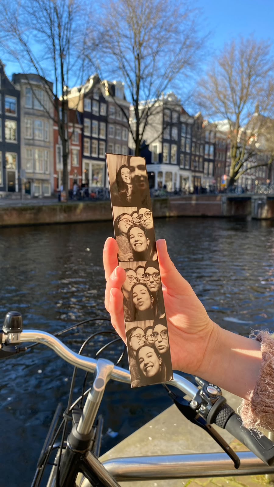 Photo-booth strip held up in front of an Amsterdam canal