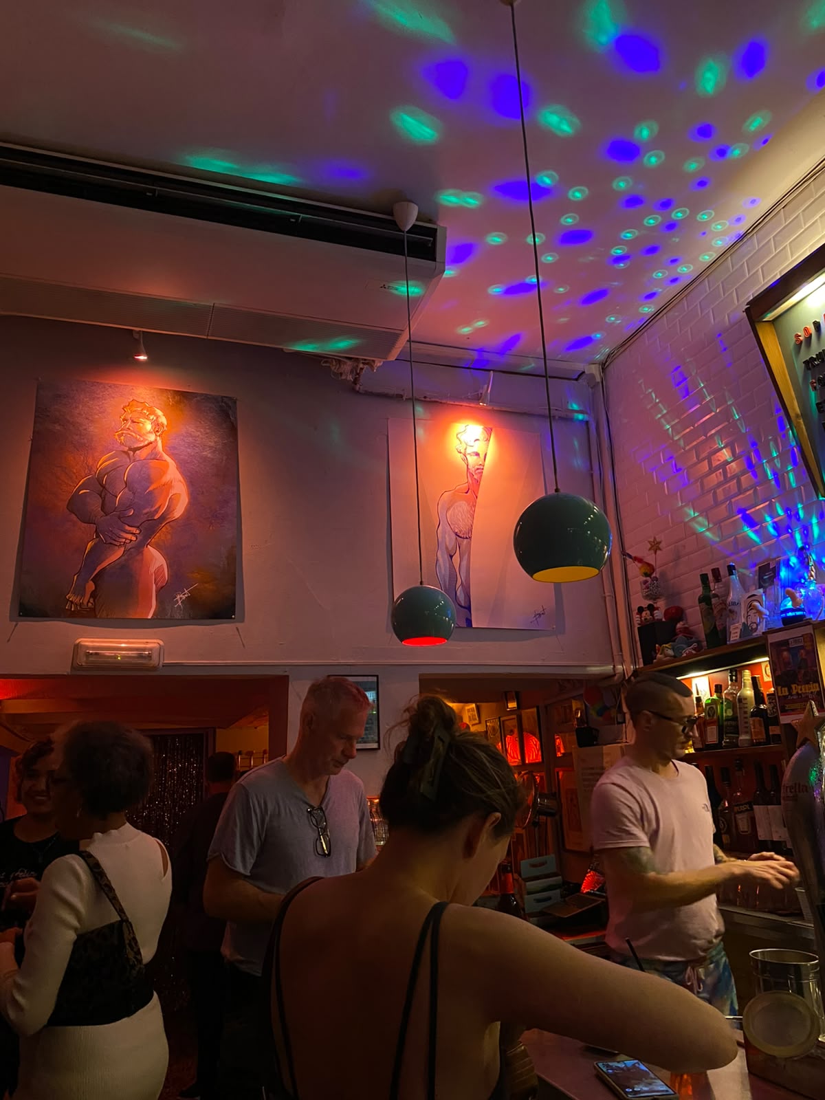 Queer bar in Barcelona with disco lights and male nude illustrations on the wall