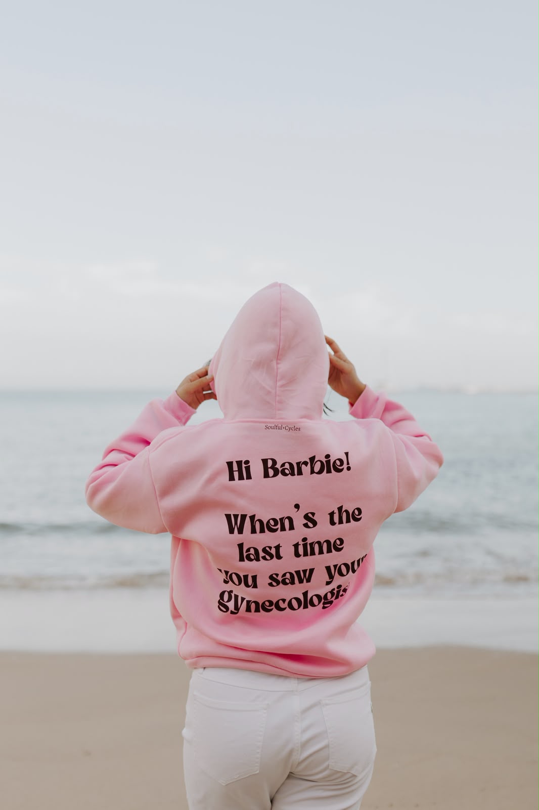 Back of a pink hoodie printed 'Hi Barbie! When's the last time you saw your gynecologist?'