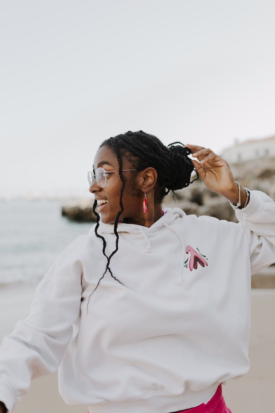 Woman laughing on the beach in a white hoodie with a clitoris illustration