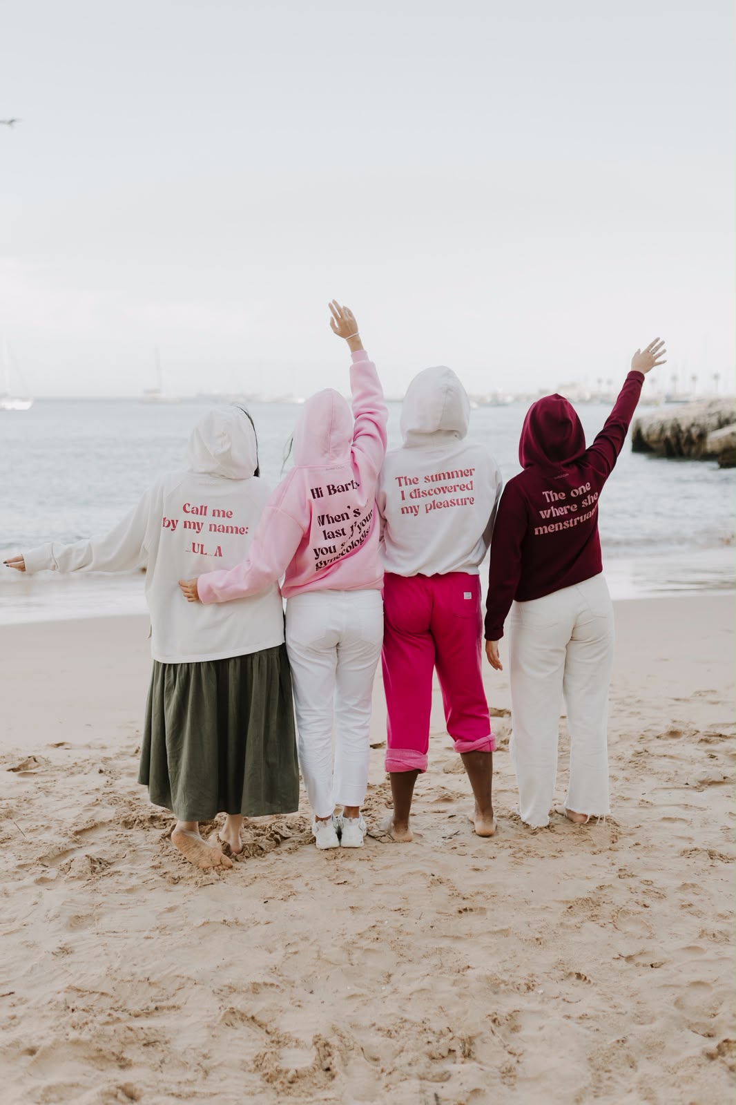 The same four friends from behind, showing the slogans on the backs of their hoodies