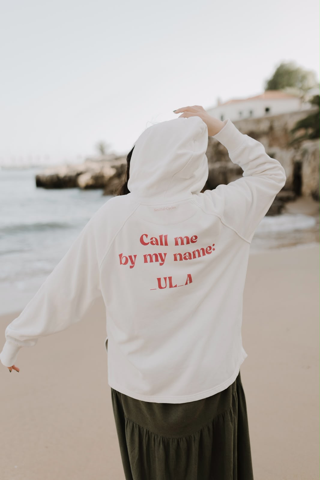 Back of a cream hoodie printed 'Call me by my name: _UL_A'