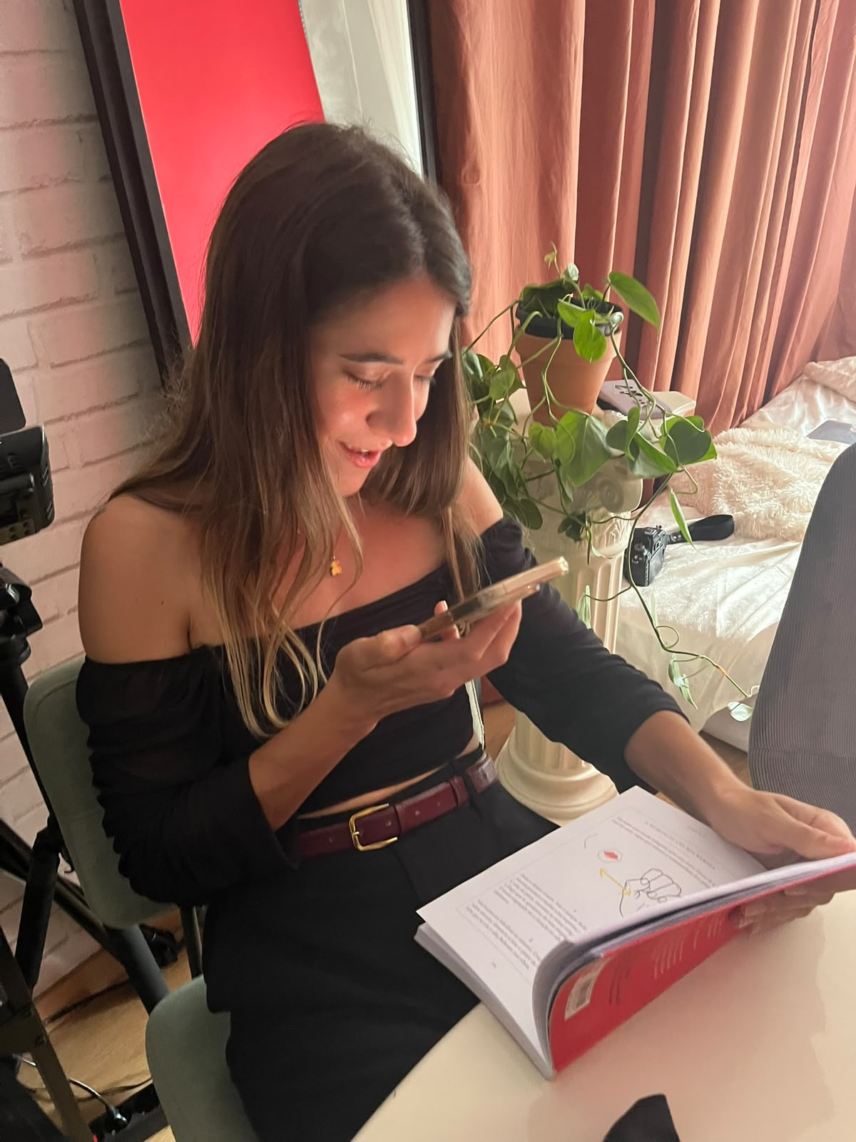 Mariana smiling while reading from a book and holding her phone during a hen party
