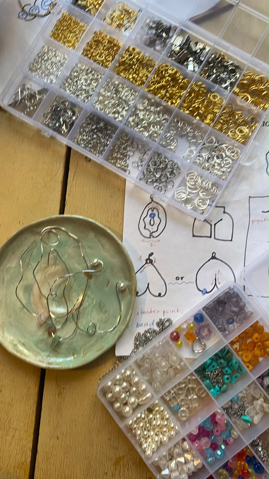 Jewellery workshop table with beads, rings and hand-drawn vulva earring designs