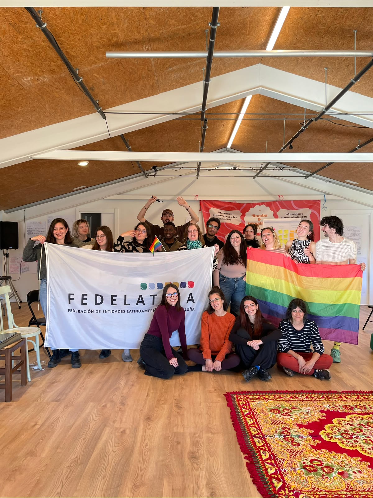 Training course participants posing with a FEDELATINA banner and a rainbow flag